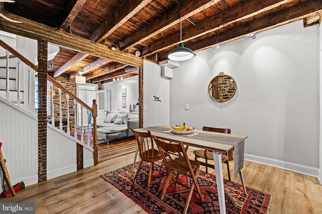 dining space featuring light wood-style flooring, beam ceiling, baseboards, stairway, and wood ceiling
