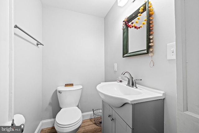 bathroom with baseboards, wood finished floors, vanity, and toilet