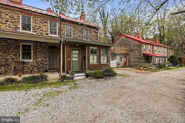 view of front of home featuring gravel driveway and a chimney
