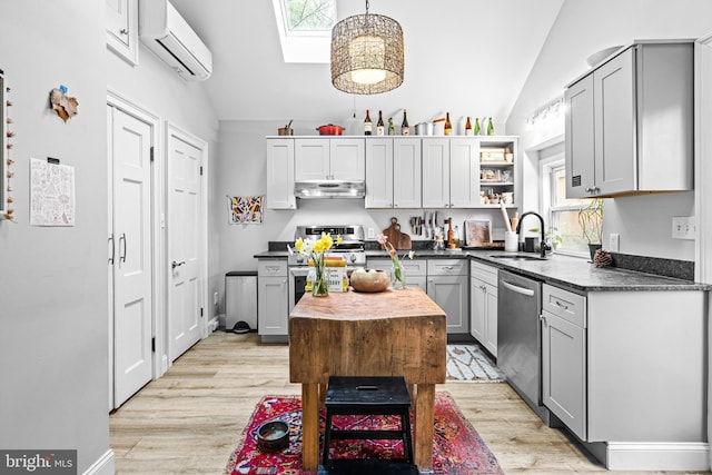 kitchen with an AC wall unit, lofted ceiling with skylight, a sink, stainless steel appliances, and under cabinet range hood