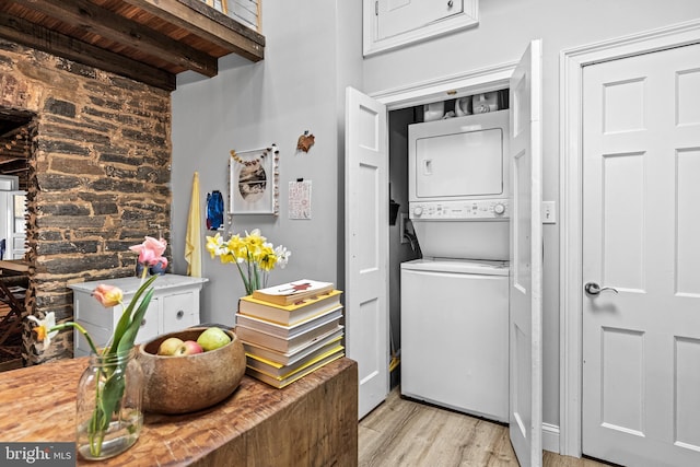 laundry room with wooden ceiling, stacked washer / dryer, laundry area, and light wood-style flooring