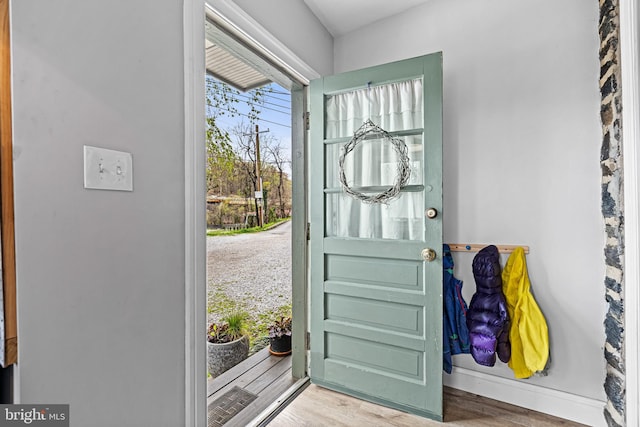 doorway with wood finished floors and baseboards