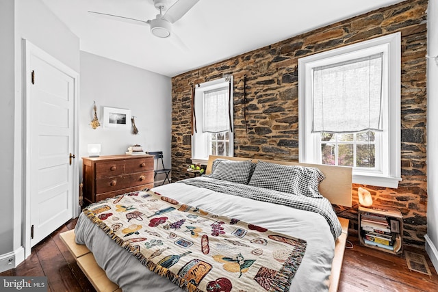 bedroom featuring wood-type flooring, a ceiling fan, and multiple windows