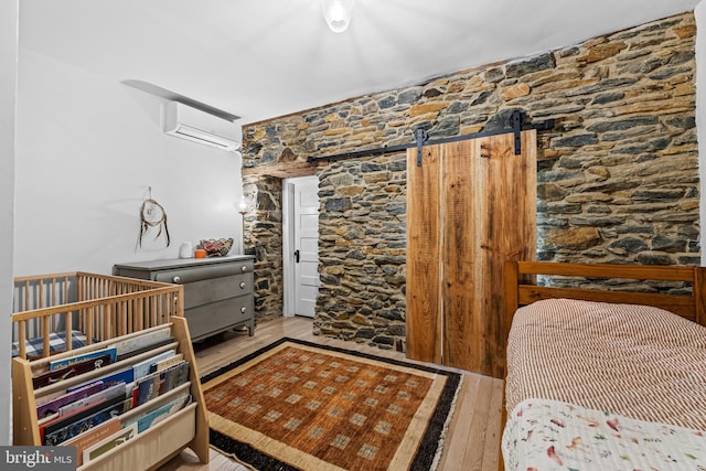 bedroom with wood finished floors and a wall unit AC