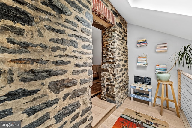 corridor featuring lofted ceiling and wood finished floors