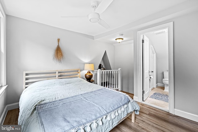 bedroom featuring wood finished floors, ensuite bath, a ceiling fan, and baseboards