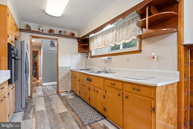 kitchen with open shelves, light countertops, a sink, light wood-style floors, and black appliances