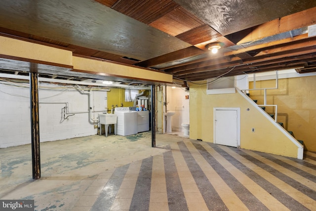 unfinished basement featuring a sink, washer and dryer, and stairway