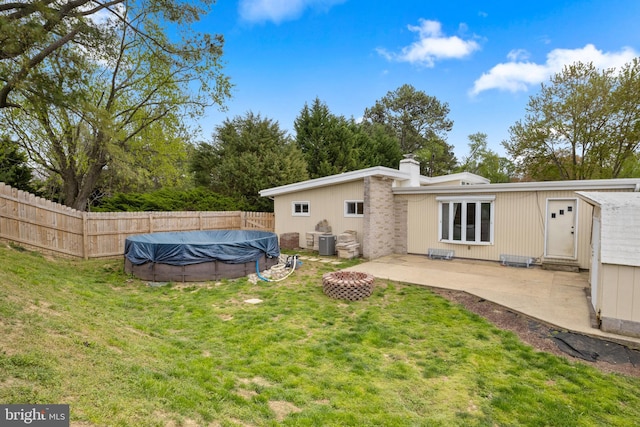 rear view of property with a patio area, a lawn, a chimney, fence, and a fenced in pool