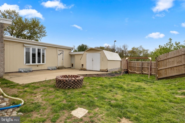 rear view of house with fence, a storage shed, an outdoor structure, a patio, and a lawn