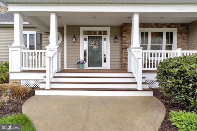 doorway to property featuring a porch and stone siding