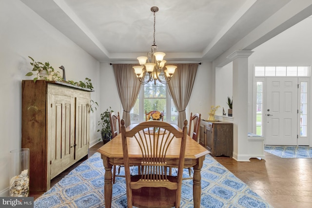 dining room featuring wood finished floors, baseboards, an inviting chandelier, and a raised ceiling