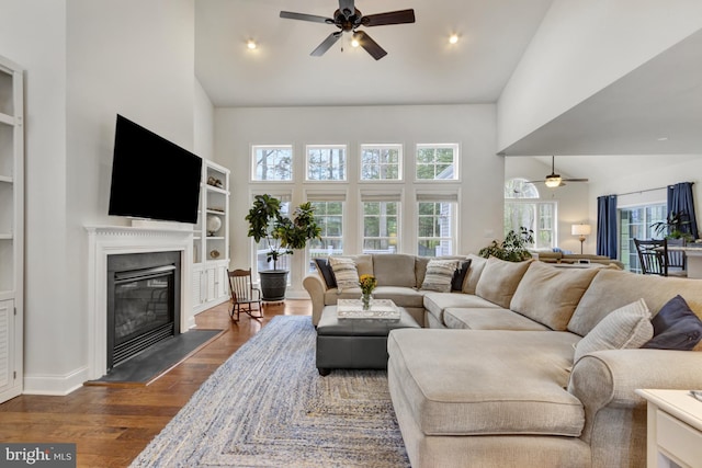living room featuring a glass covered fireplace, recessed lighting, dark wood-style floors, ceiling fan, and high vaulted ceiling