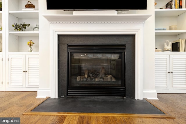 interior details featuring a fireplace with flush hearth and wood finished floors