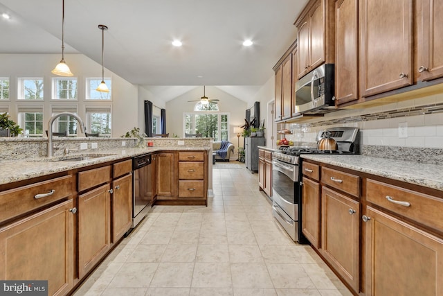 kitchen with vaulted ceiling, backsplash, brown cabinetry, appliances with stainless steel finishes, and a sink