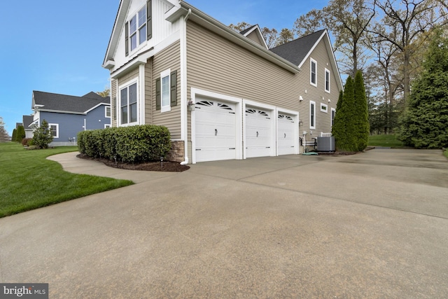 view of side of home featuring a lawn, an attached garage, cooling unit, and driveway