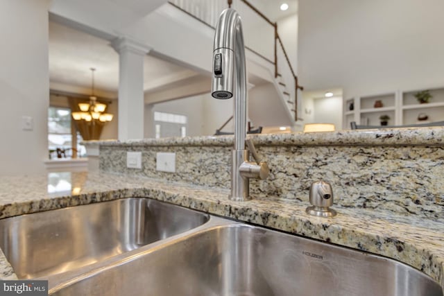 interior details featuring light stone countertops, a sink, and an inviting chandelier