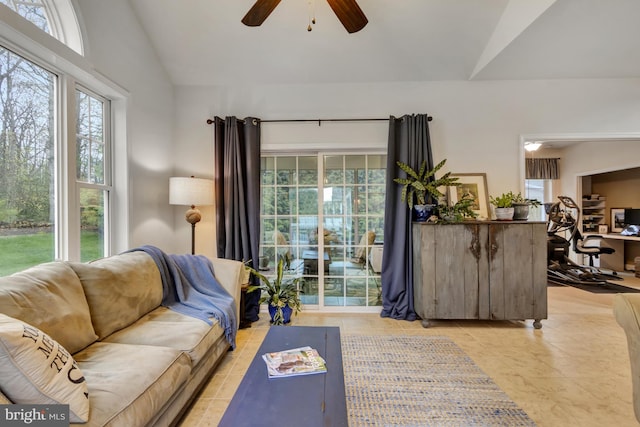 living room with ceiling fan, a wealth of natural light, vaulted ceiling, and light tile patterned flooring