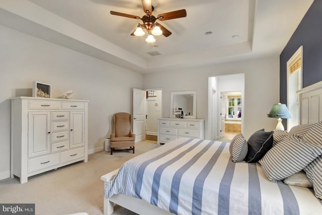 bedroom featuring visible vents, baseboards, a raised ceiling, connected bathroom, and light colored carpet