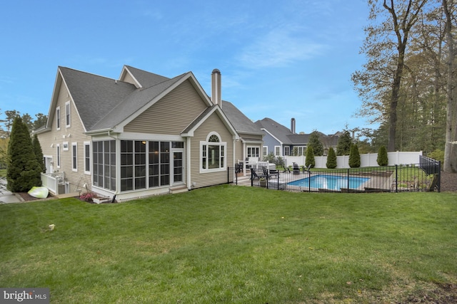 back of property featuring a yard, fence, a fenced in pool, and a sunroom