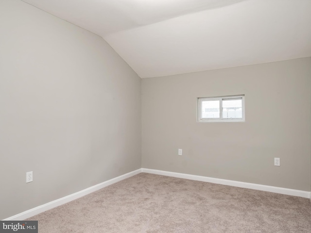 empty room with lofted ceiling, carpet flooring, and baseboards