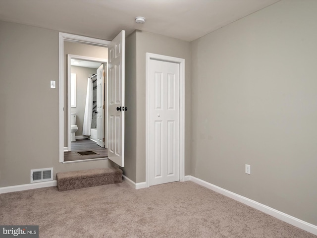 unfurnished bedroom featuring carpet, baseboards, visible vents, and a closet