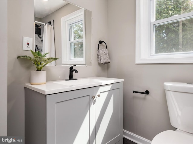 bathroom featuring toilet, vanity, and baseboards