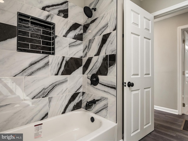 bathroom featuring baseboards, wood finished floors, and shower / tub combination