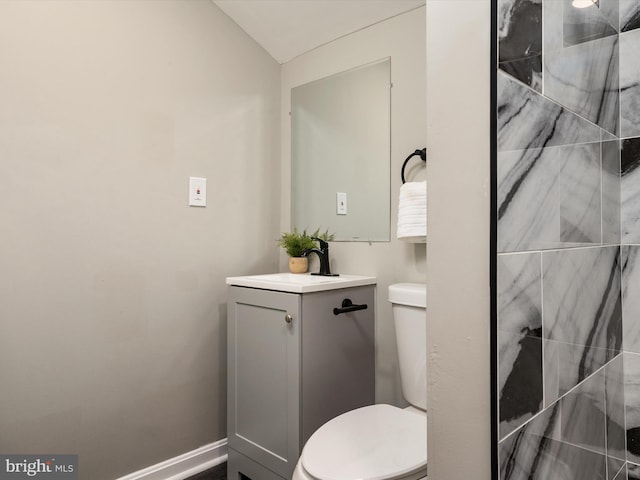 bathroom featuring vaulted ceiling, toilet, and vanity