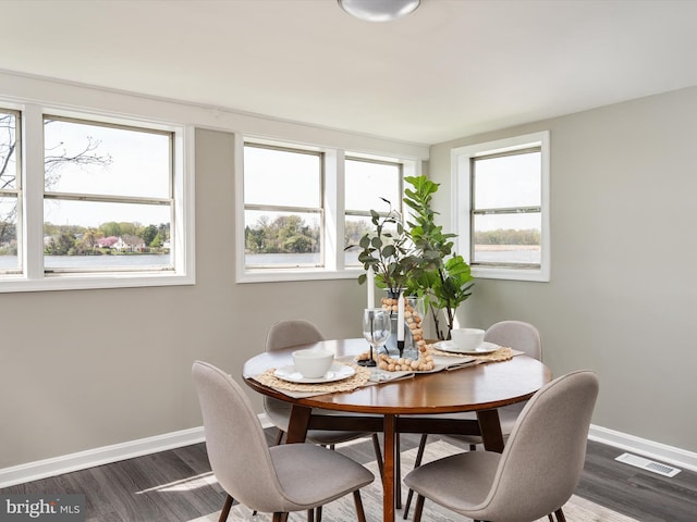dining room featuring wood finished floors, visible vents, and baseboards