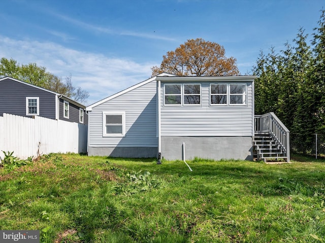 view of home's exterior with fence, a yard, and stairway