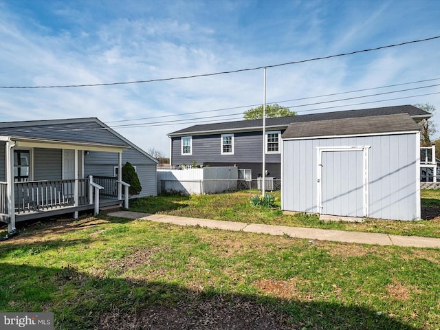view of yard with a storage shed, a porch, fence, and an outdoor structure
