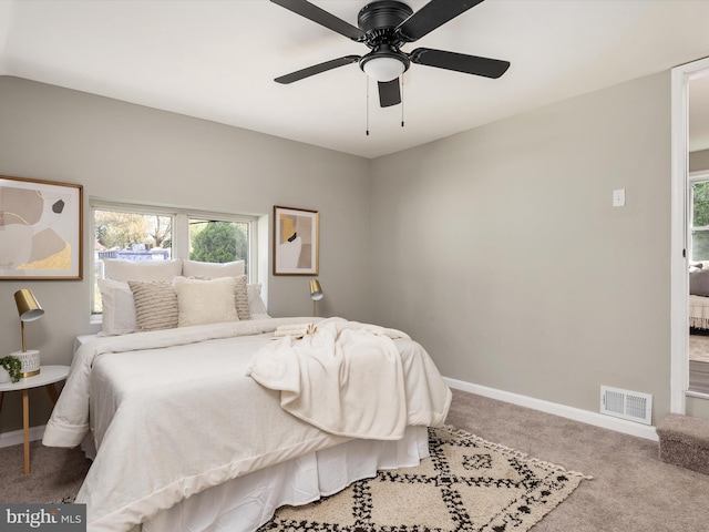 carpeted bedroom featuring baseboards, visible vents, and multiple windows