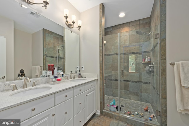 bathroom with a stall shower, double vanity, and a sink