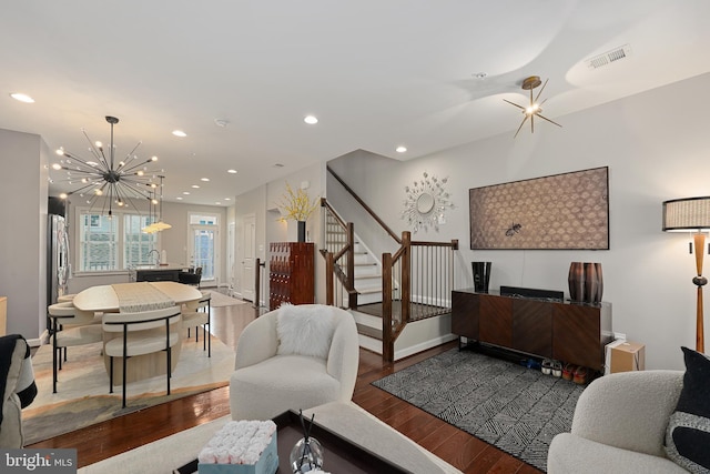 living area featuring visible vents, an inviting chandelier, recessed lighting, wood finished floors, and stairs