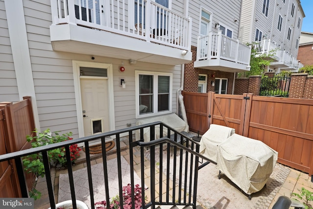 view of patio / terrace with a gate, a fenced backyard, and a balcony
