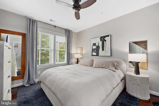 bedroom with a ceiling fan, visible vents, dark wood-style flooring, and baseboards