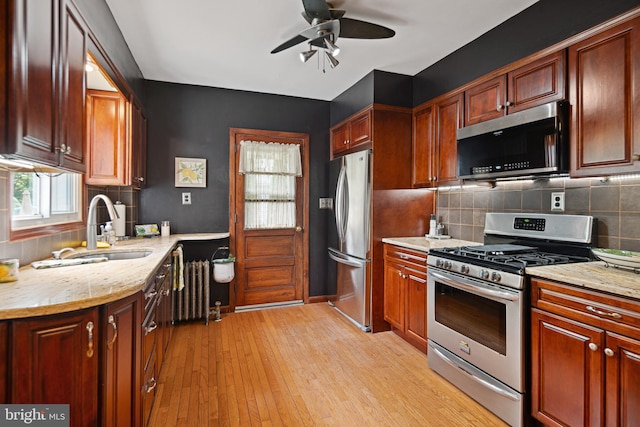 kitchen with decorative backsplash, appliances with stainless steel finishes, ceiling fan, and light stone countertops