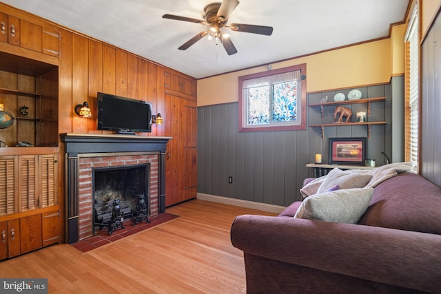 living room featuring wooden walls, ceiling fan, light wood finished floors, and a fireplace