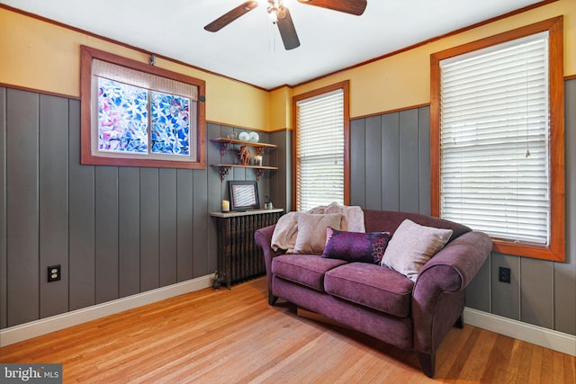 living room with baseboards, ceiling fan, a wainscoted wall, and wood finished floors