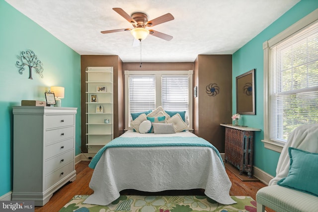 bedroom featuring baseboards, multiple windows, wood finished floors, and radiator
