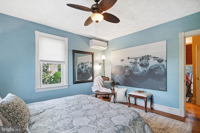 bedroom featuring baseboards, a wall mounted air conditioner, a ceiling fan, and wood finished floors