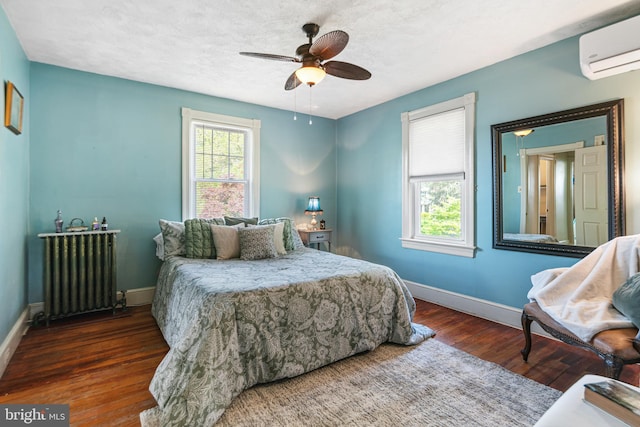 bedroom featuring baseboards, a wall mounted air conditioner, radiator heating unit, and wood finished floors