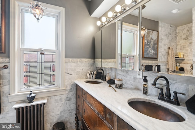 bathroom featuring double vanity, tile walls, a sink, and radiator