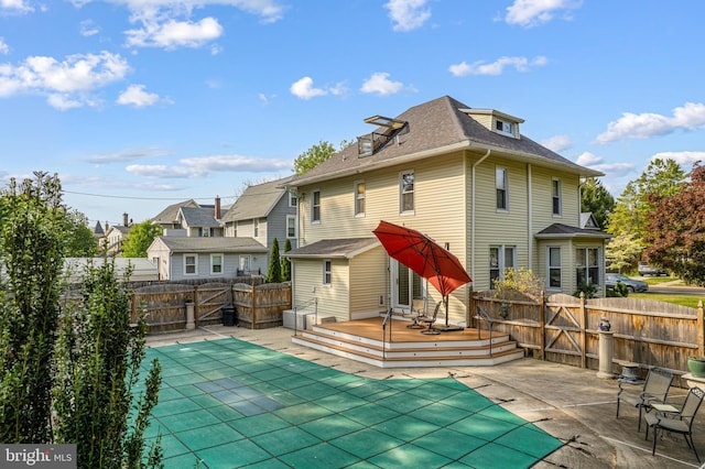 back of property featuring a residential view, a wooden deck, a fenced backyard, a fenced in pool, and a patio area