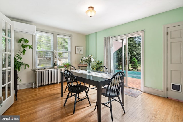 dining room featuring a wall mounted AC, light wood-style flooring, and radiator