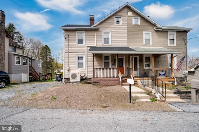view of front of house with a porch, a chimney, ac unit, and stairway