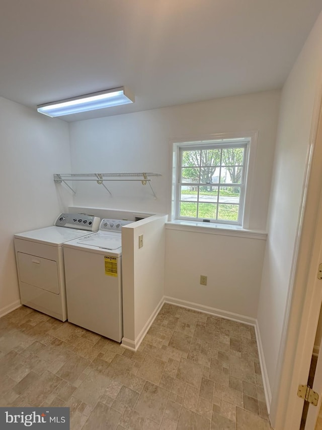 laundry room featuring baseboards, stone finish flooring, laundry area, and independent washer and dryer