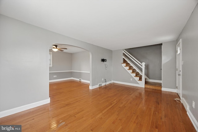 510 W S Ave, Glenolden, PA 19036 - unfurnished living room featuring baseboards, arched walkways, a ceiling fan, light wood-style floors, and stairway