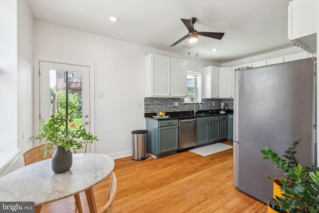 kitchen featuring decorative backsplash, light wood-style floors, white cabinets, a ceiling fan, and appliances with stainless steel finishes